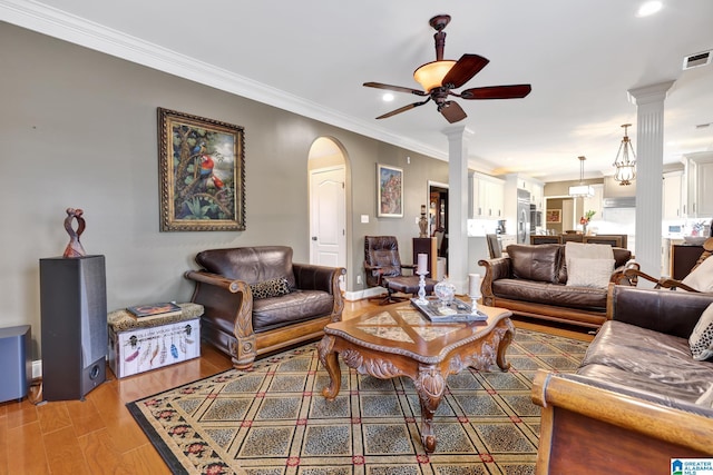 living room featuring a ceiling fan, visible vents, crown molding, and light wood-style flooring