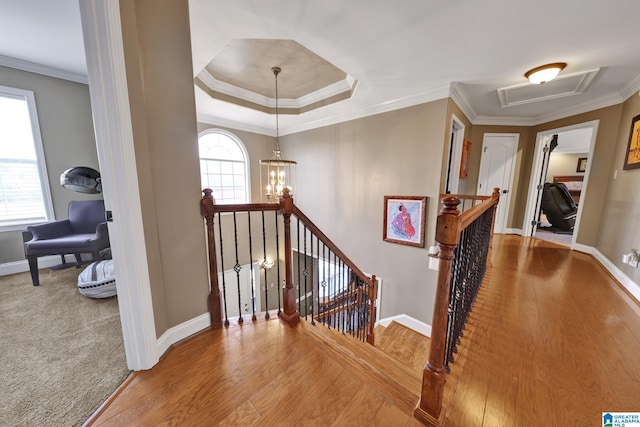 stairway featuring a healthy amount of sunlight, crown molding, and wood finished floors