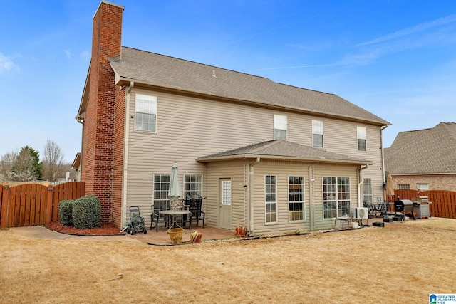 back of property featuring a shingled roof, a chimney, a gate, fence, and a patio area