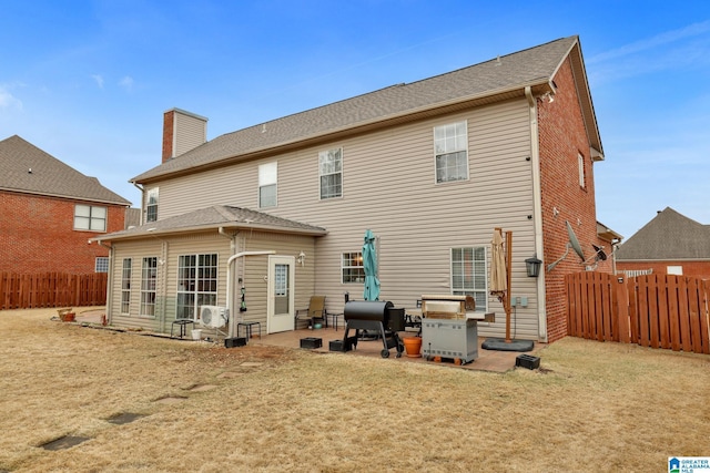 back of house with a patio area, a lawn, a chimney, and a fenced backyard