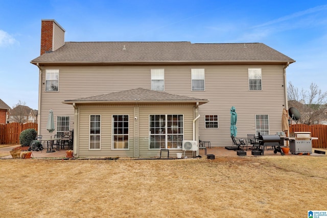 rear view of house featuring a yard, a patio area, fence, and a chimney