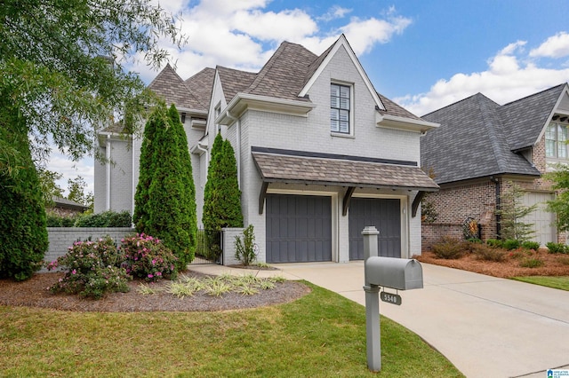 view of front of home with an attached garage, driveway, a front lawn, and brick siding