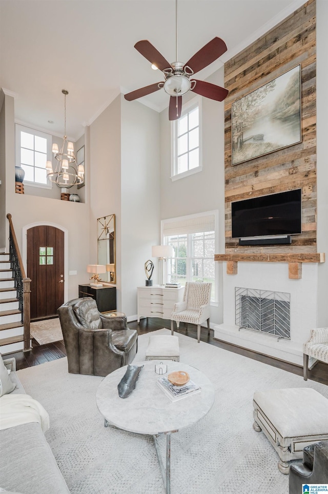 living room featuring stairs, a fireplace, wood finished floors, and a towering ceiling