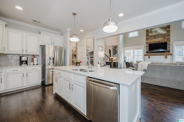 kitchen with a sink, visible vents, open floor plan, ornamental molding, and appliances with stainless steel finishes