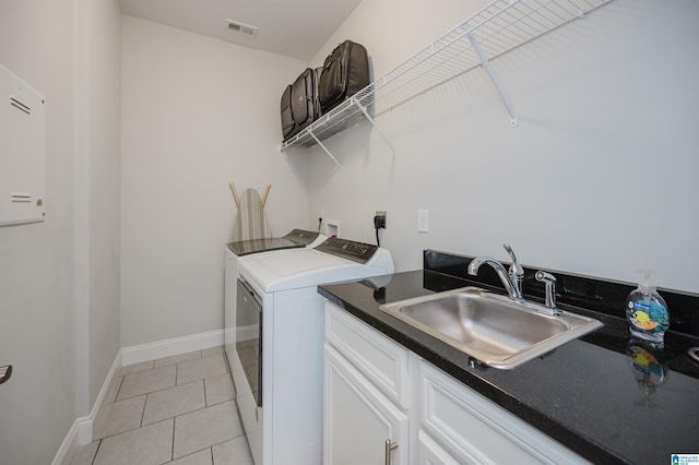 washroom with light tile patterned floors, a sink, visible vents, washer and dryer, and cabinet space