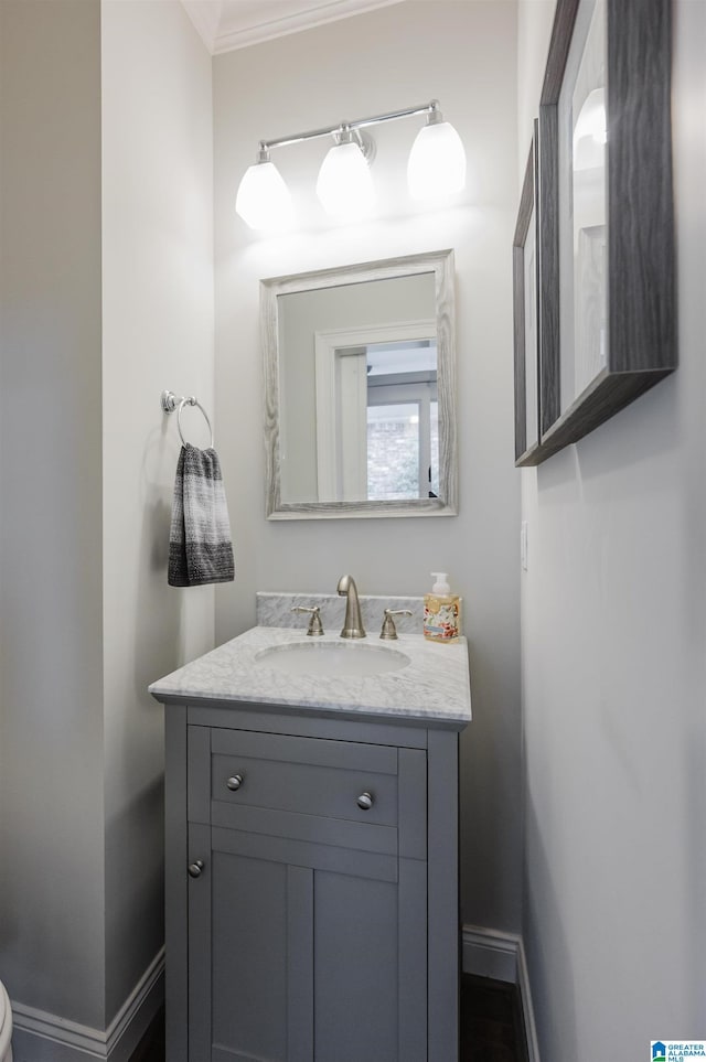 bathroom featuring ornamental molding, vanity, and baseboards