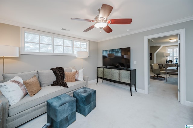 living room with light carpet, baseboards, visible vents, ceiling fan, and crown molding