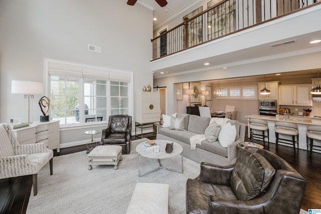 living room featuring ceiling fan, ornamental molding, wood finished floors, and visible vents