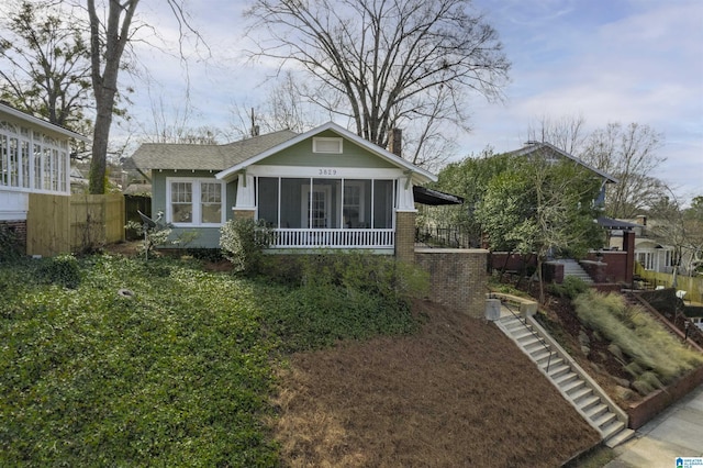 view of front facade with a sunroom, fence, and stairs