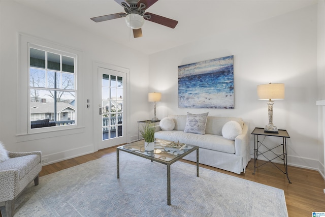 living area featuring ceiling fan, wood finished floors, and baseboards