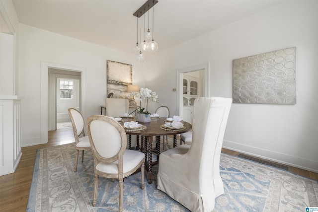 dining area with wood finished floors, visible vents, and baseboards