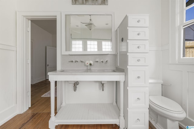 bathroom featuring wainscoting, wood finished floors, toilet, and decorative backsplash