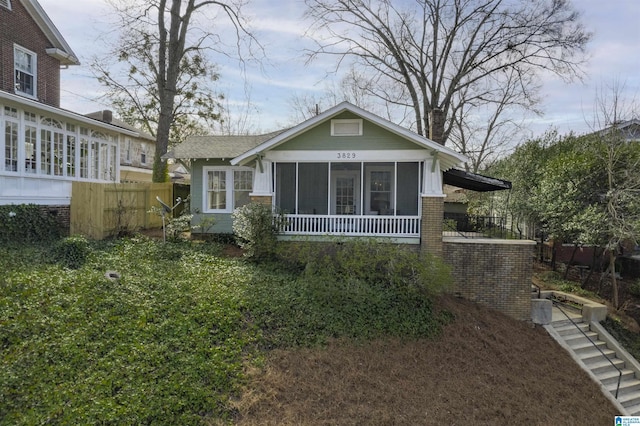 view of front of property with brick siding, fence, and a sunroom