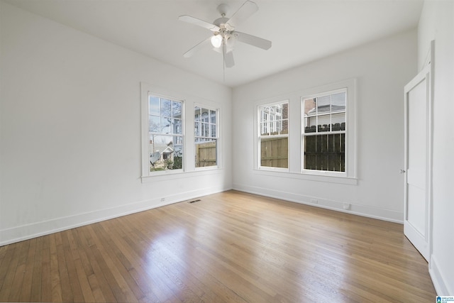 empty room with a ceiling fan, light wood-type flooring, visible vents, and baseboards