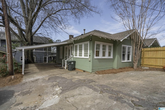 view of side of home with a carport, driveway, and fence