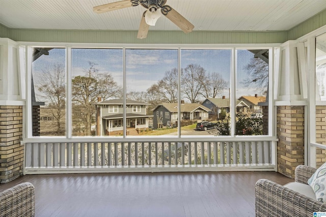 sunroom featuring a residential view and a ceiling fan