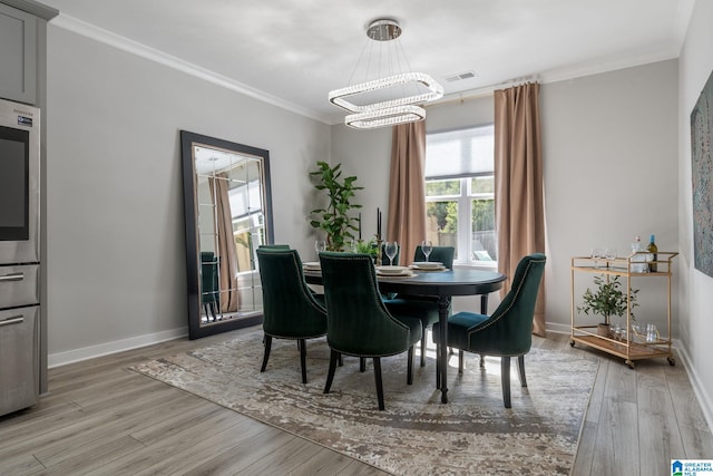 dining area with a chandelier, visible vents, baseboards, light wood-type flooring, and crown molding