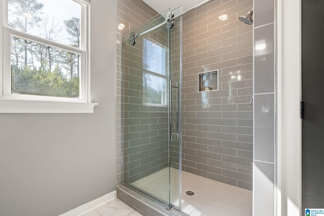 bathroom with a stall shower, marble finish floor, and baseboards