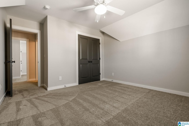 unfurnished bedroom with vaulted ceiling, a closet, carpet, and baseboards