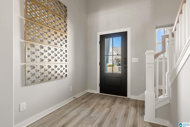 foyer with stairs, light wood-style flooring, and baseboards