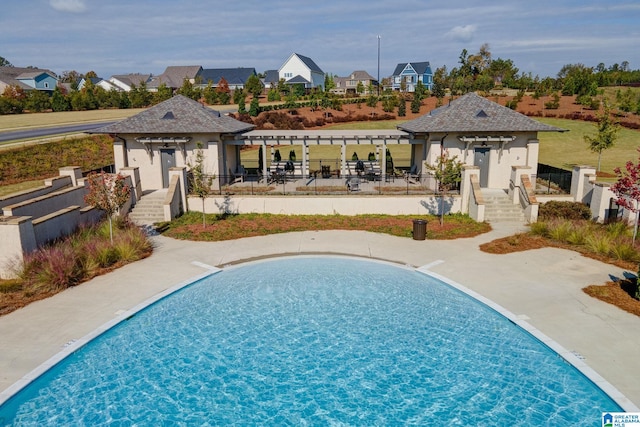 rear view of house featuring a fenced in pool, a patio, fence, a pergola, and a residential view