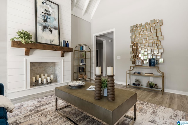 living room featuring a fireplace, wood finished floors, beam ceiling, and baseboards