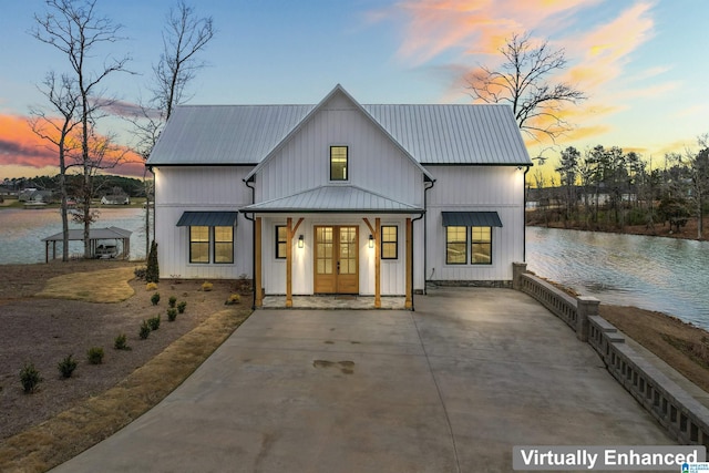 view of front of house with metal roof, a water view, french doors, board and batten siding, and a standing seam roof