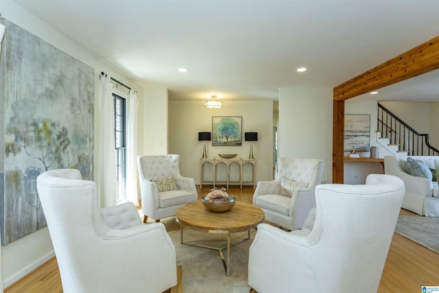 living area featuring stairs, beam ceiling, light wood-style flooring, and recessed lighting