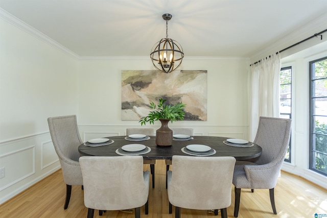 dining area featuring ornamental molding, wood finished floors, an inviting chandelier, wainscoting, and a decorative wall