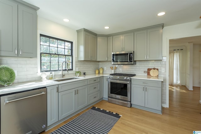 kitchen with a sink, light countertops, gray cabinets, and stainless steel appliances