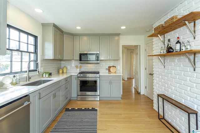 kitchen featuring gray cabinetry, stainless steel appliances, light countertops, and a sink