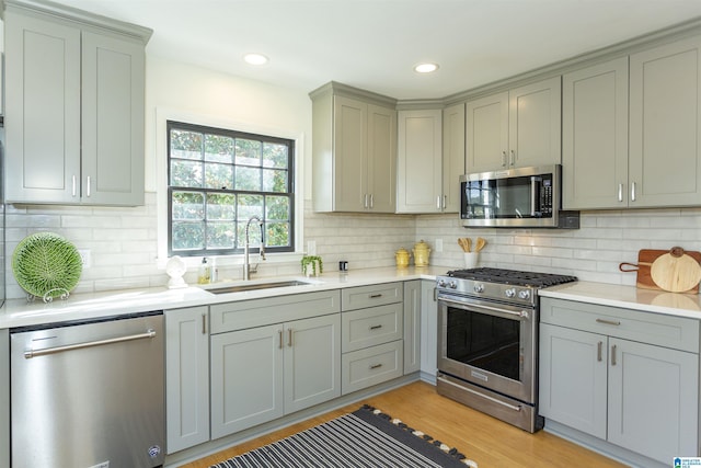 kitchen with a sink, stainless steel appliances, gray cabinetry, and light countertops