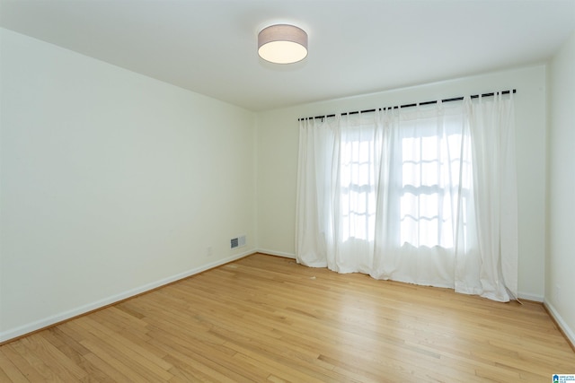 spare room with light wood-style floors, visible vents, and baseboards