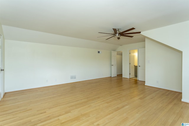 interior space featuring light wood-type flooring, visible vents, a ceiling fan, baseboards, and vaulted ceiling