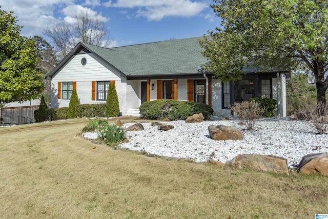 view of front of house with brick siding, a shingled roof, and a front lawn