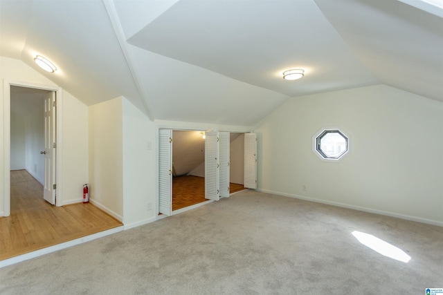 additional living space with baseboards, carpet, and vaulted ceiling