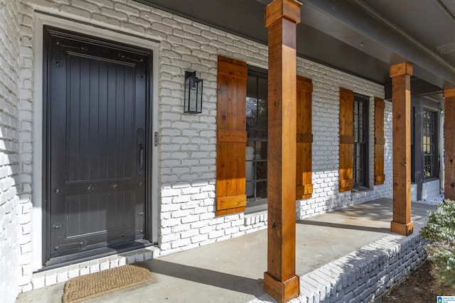 entrance to property with brick siding and a porch