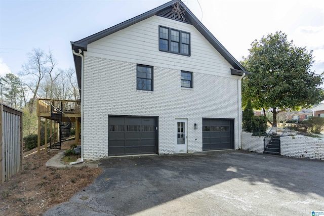 view of side of home with brick siding, driveway, stairs, and a garage