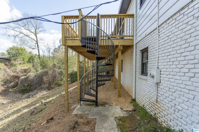 view of home's exterior with stairs, brick siding, and a wooden deck