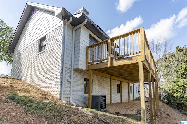 view of property exterior with a deck, central AC unit, and brick siding