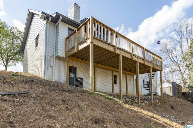 rear view of house with brick siding, a chimney, stairs, and a deck