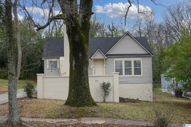 view of front of home with a shingled roof and brick siding