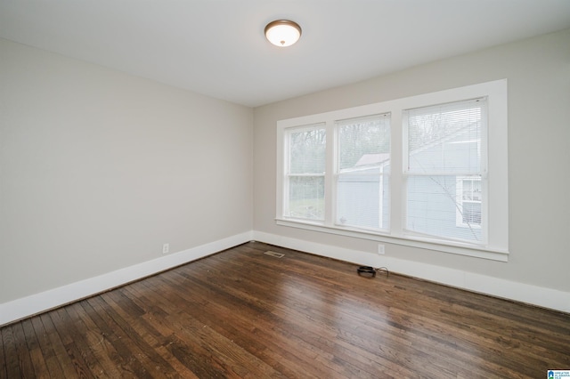 empty room with visible vents, baseboards, and dark wood-style flooring