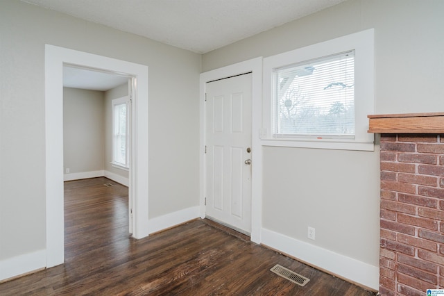 foyer with wood finished floors, visible vents, and baseboards