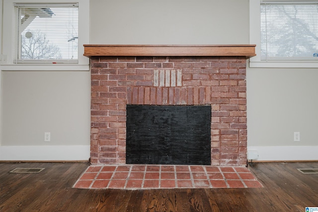 interior details featuring baseboards, a fireplace, visible vents, and wood finished floors