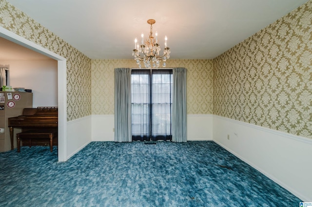 carpeted empty room with wainscoting, an inviting chandelier, and wallpapered walls