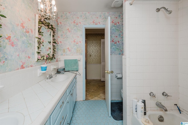 bathroom featuring double vanity, wainscoting, a sink, and wallpapered walls