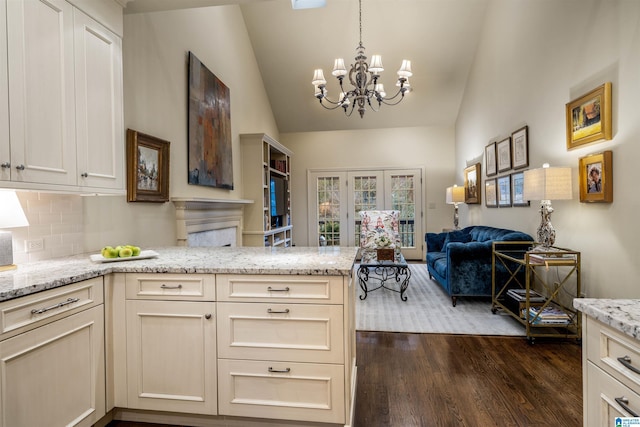 kitchen featuring a notable chandelier, light stone counters, dark wood finished floors, open floor plan, and lofted ceiling