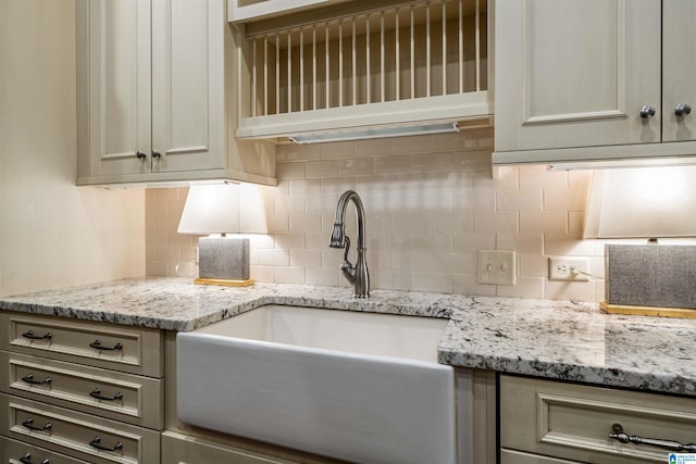 kitchen with a sink, decorative backsplash, and light stone countertops