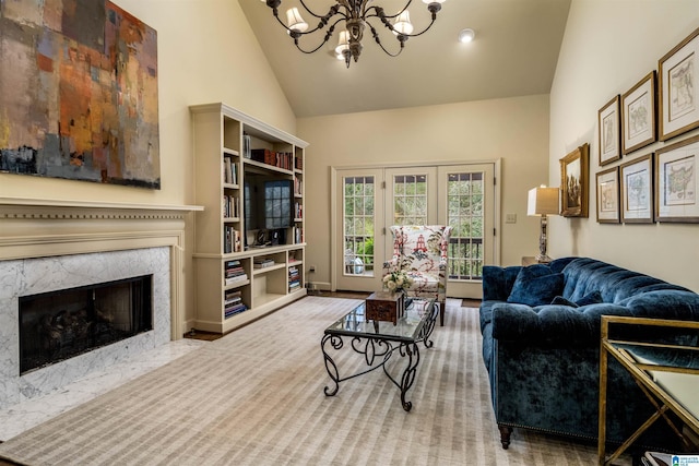 living room featuring high vaulted ceiling, a notable chandelier, baseboards, and a premium fireplace